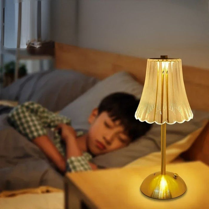 Abajur de Mesa Clássica Elegance dourado aceso ao lado de criança dormindo, luz quente e suave ideal para quarto.
