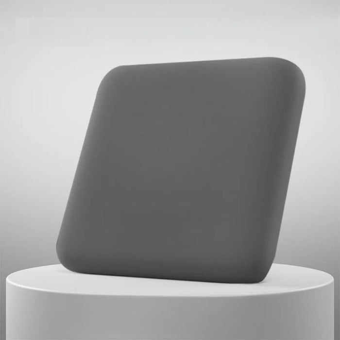 Almofada ergonômica cinza escuro posicionada sobre pedestal branco, destacando seu design moderno e macio.