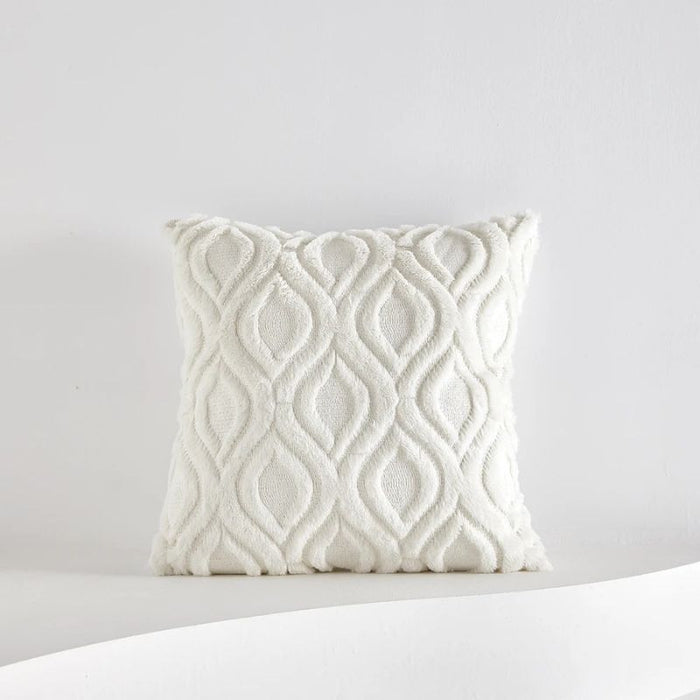 Capa de almofada peluciada branca com padrão elegante de ondas em relevo sobre fundo neutro.