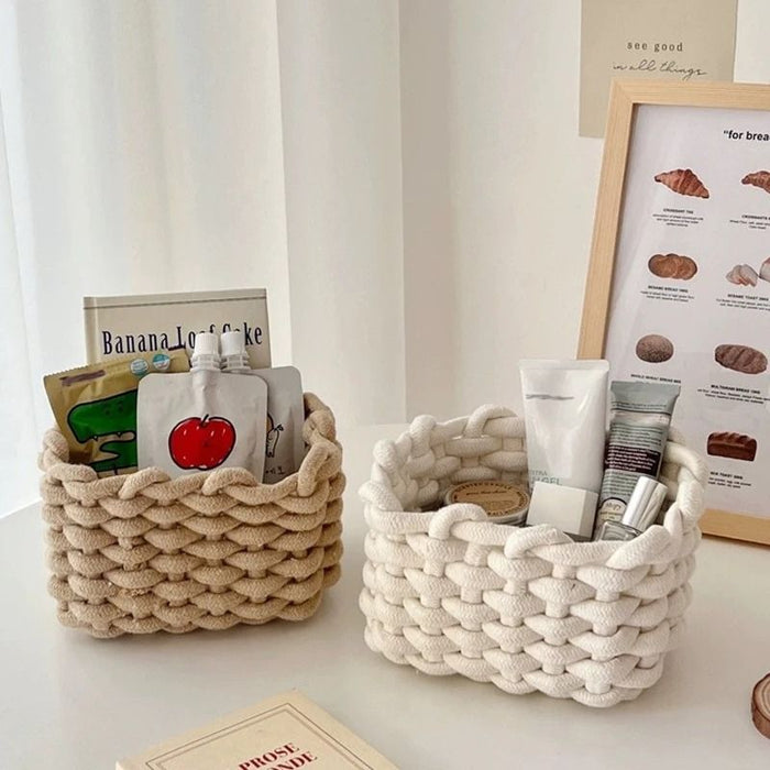 Dois cestos artesanais trançados em corda de algodão nas cores bege e branca, utilizados para guardar cosméticos e objetos decorativos em ambiente minimalista e acolhedor.